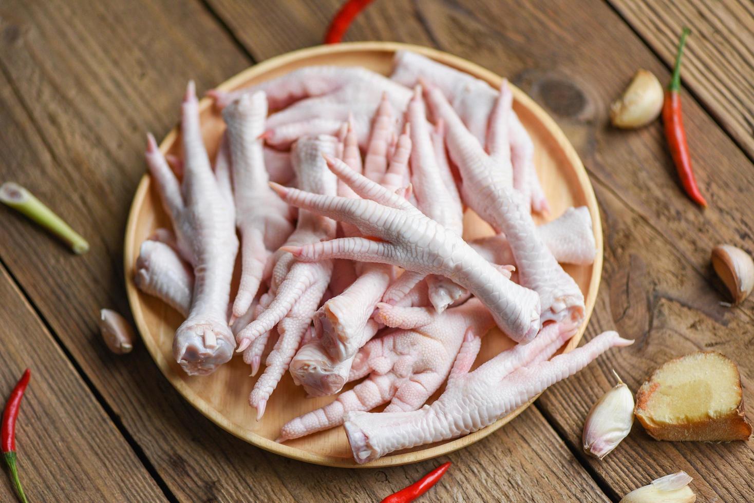 Fresh raw chicken feet for cooked food on the wooden table kitchen background, chicken feet on plate photo