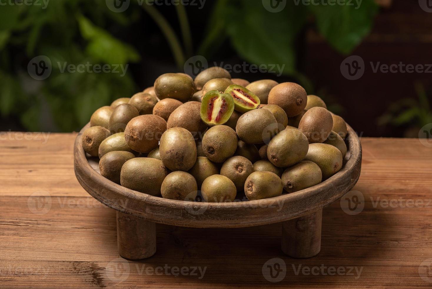 The kiwi fruit on the plate is on the wooden table photo