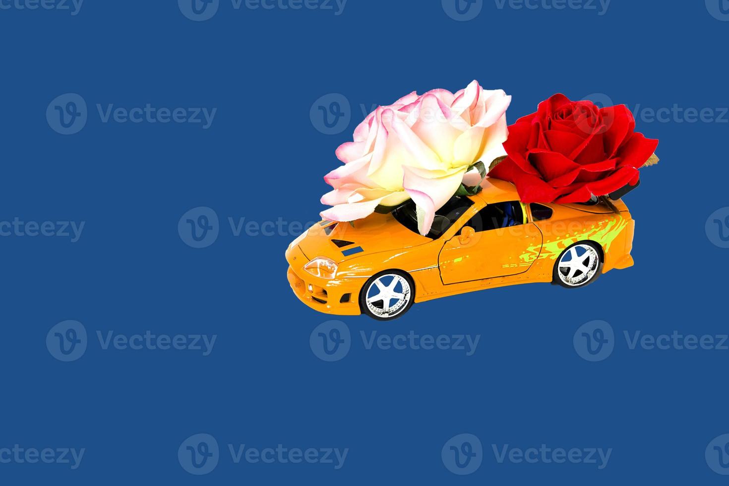 coche de juguete con rosas sobre fondo azul. foto