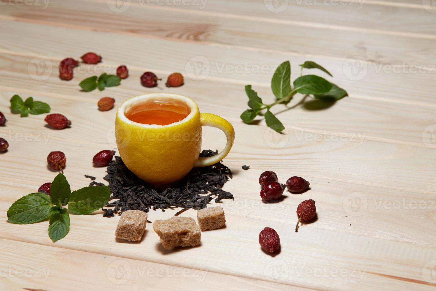 taza de té con rosas de cadera, sobre mesa de madera. una taza hecha de limón real foto