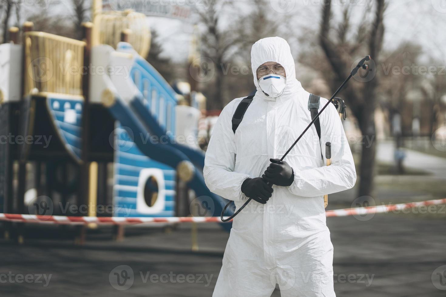Cleaning and Disinfection on the playground in the sity complex amid the coronavirus epidemic Teams for disinfection efforts Infection prevention and control of epidemic Protective suit and mask photo