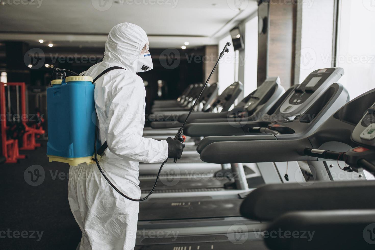 Cleaning and Disinfection in crowded places amid the coronavirus epidemic Gym cleaning and disinfection Infection prevention and control of epidemic. Protective suit and mask and spray bag photo
