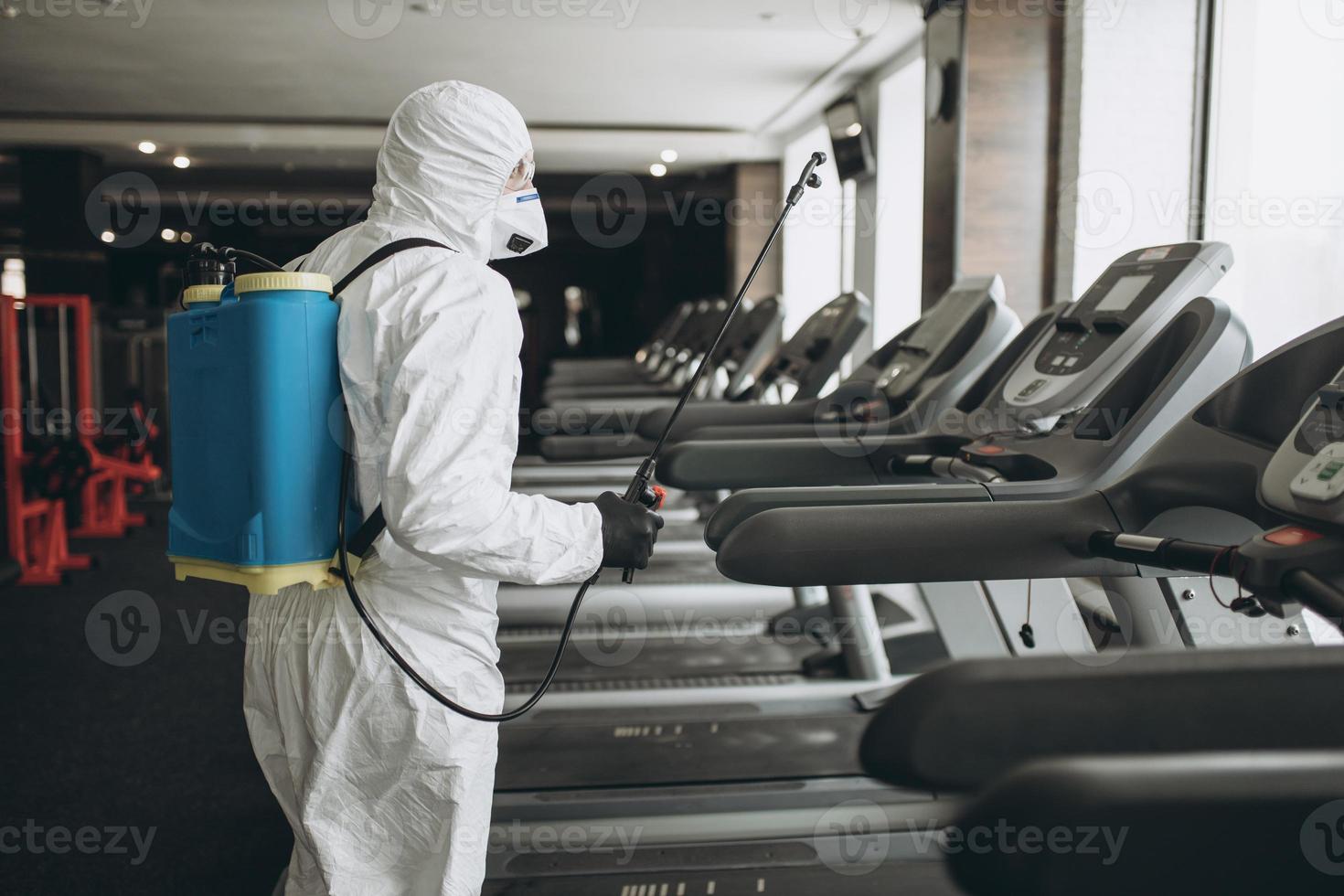 limpieza y desinfección en lugares concurridos en medio de la epidemia de coronavirus limpieza y desinfección de gimnasios prevención de infecciones y control de epidemias. traje de protección y máscara y bolsa de spray foto