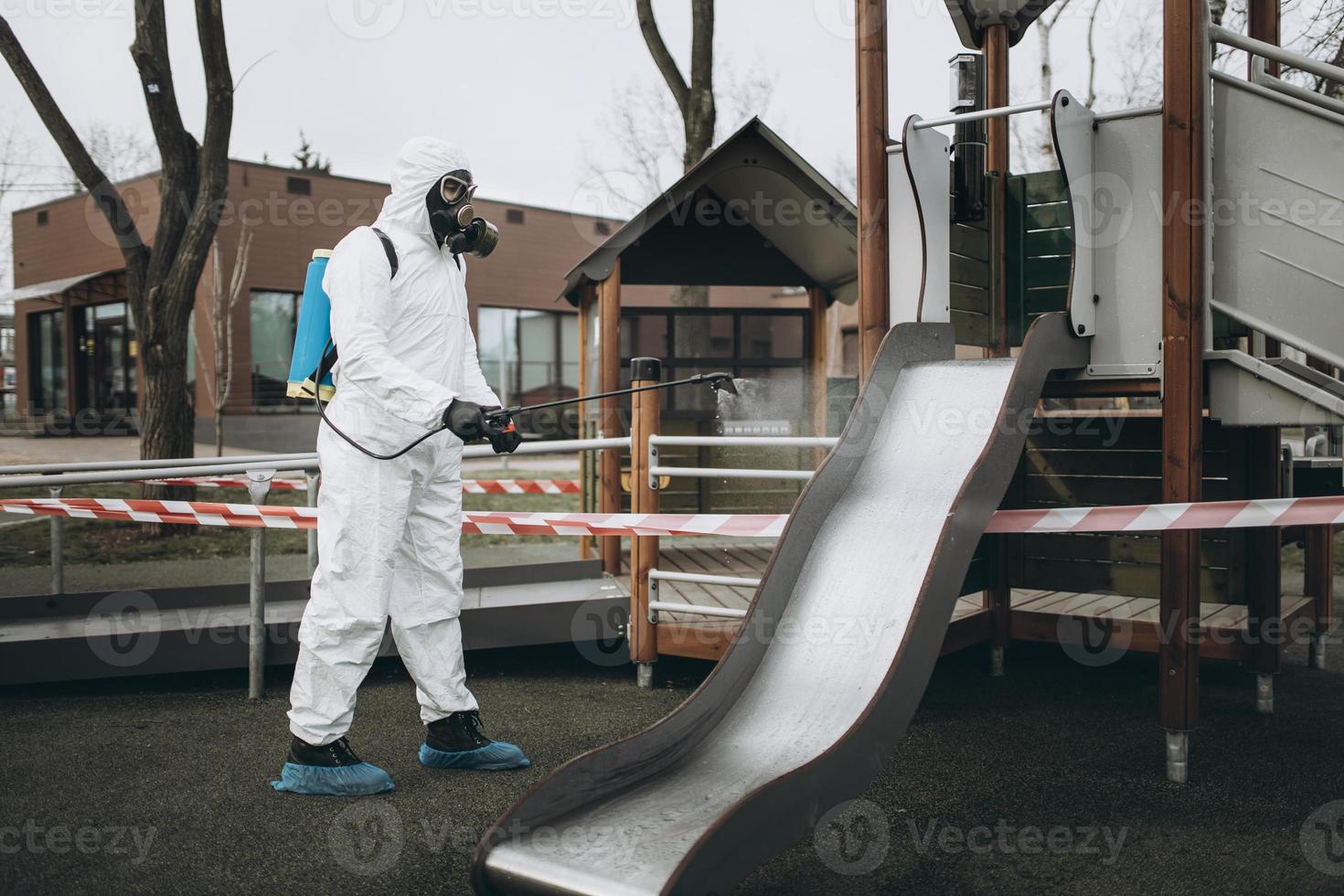 Cleaning and Disinfection on the playground in the sity complex amid the coronavirus epidemic Teams for disinfection efforts Infection prevention and control of epidemic Protective suit and mask photo