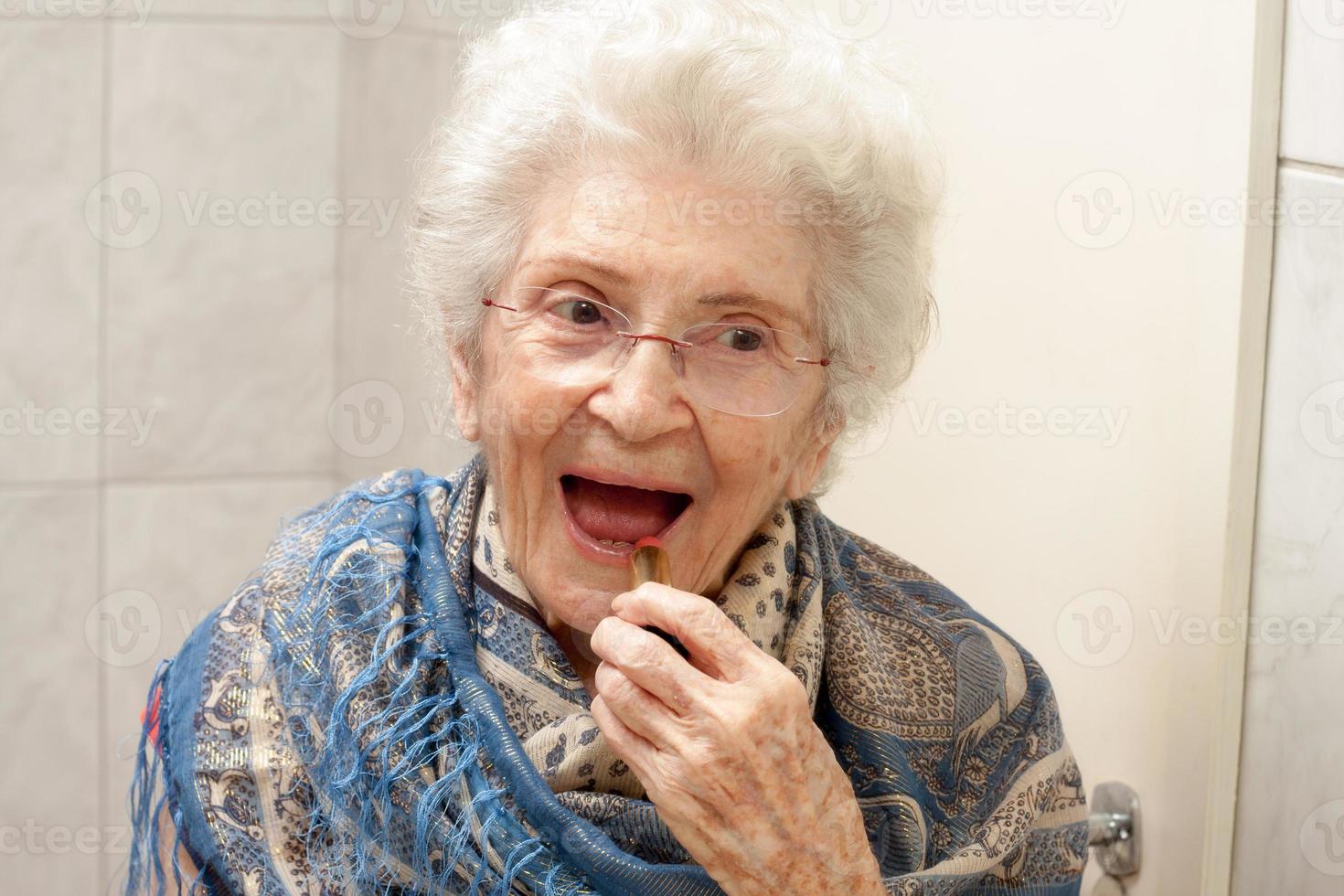 anciana aplicando lápiz labial frente a un espejo foto