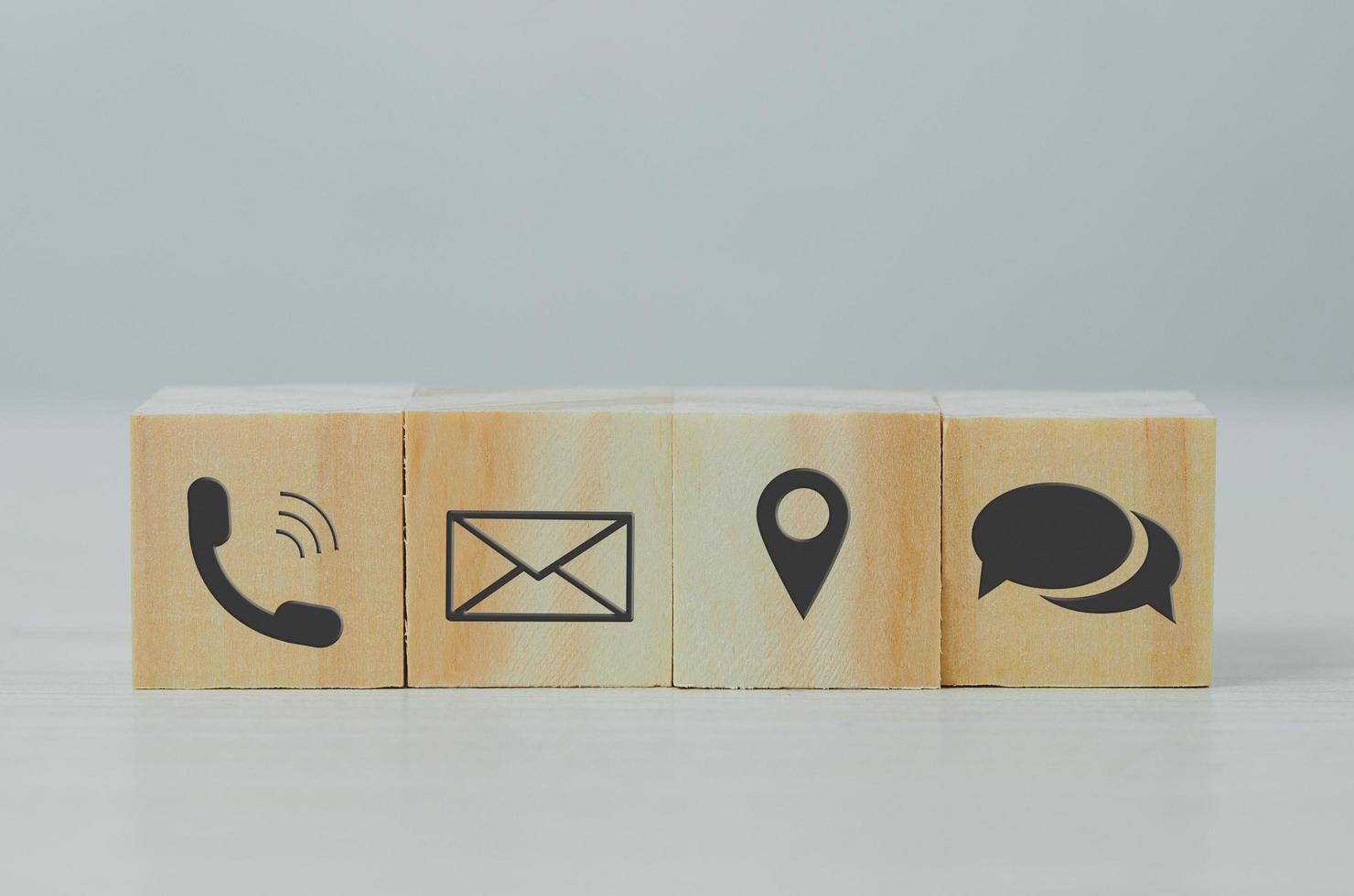 ubicación de teléfono de letra de icono de bloque de cubo de madera en la mesa. comunicación empresarial y concepto de red social. foto