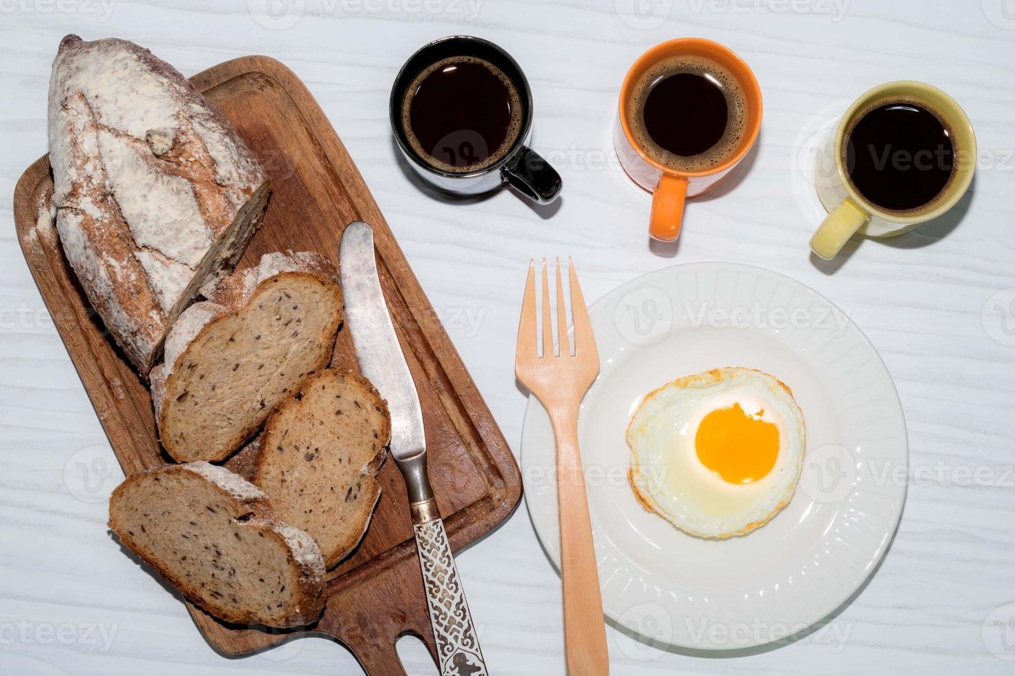 fried egg in plate bread slice in cutting board have espresso coffee on white table. photo