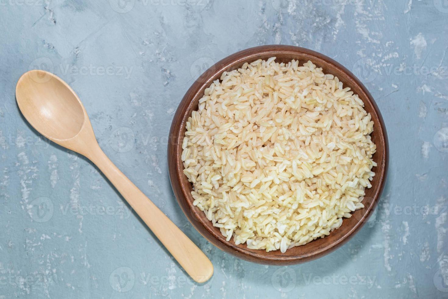 rice brown in bowl have spoon isolated on grey table background photo