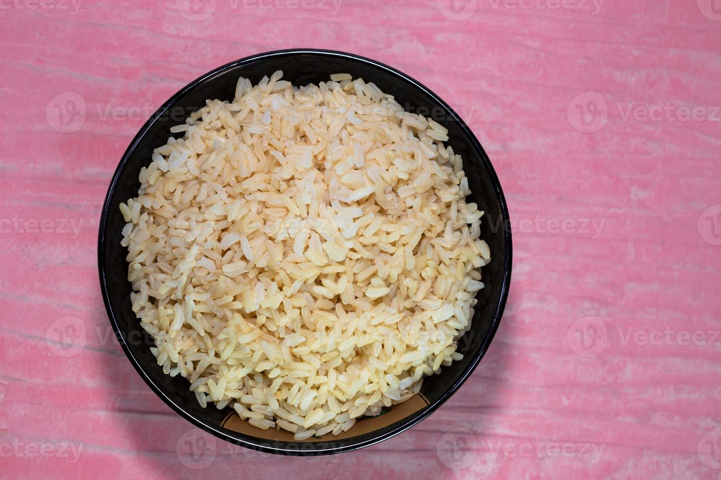 arroz marrón en tazón negro sobre mesa rosa foto