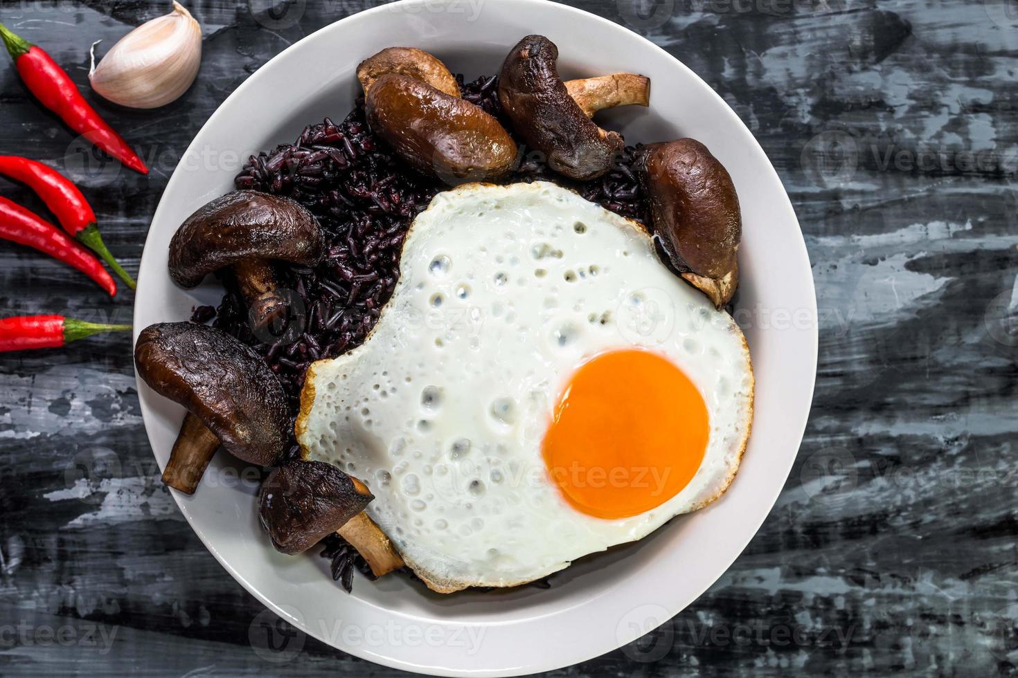 comida saludable arroz negro en un tazón con champiñones con huevo frito ajo chili hierba foto