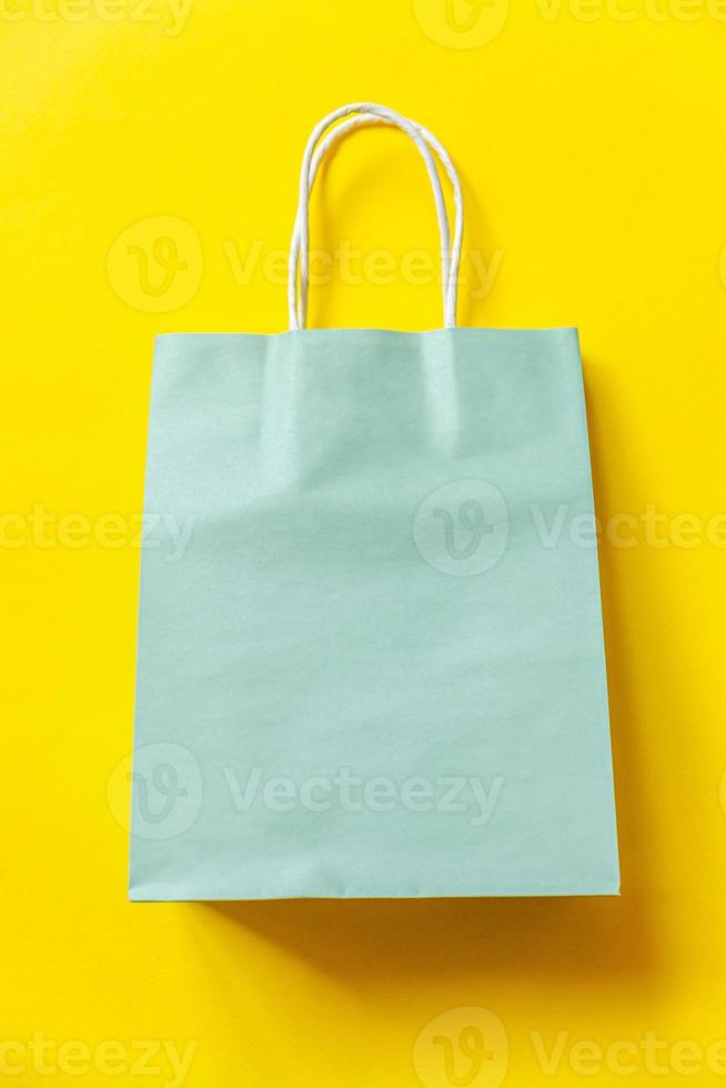 Simply minimal design shopping bag isolated on yellow background. Online or mall shopping shopaholic concept. Black friday Christmas season sale. Flat lay top view copy space, mock up photo