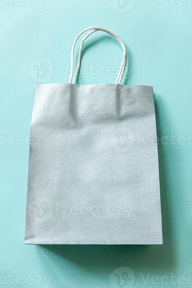 Simply minimal design shopping bag isolated on blue pastel background. Online or mall shopping shopaholic concept. Black friday Christmas season sale. Flat lay top view copy space, mock up photo