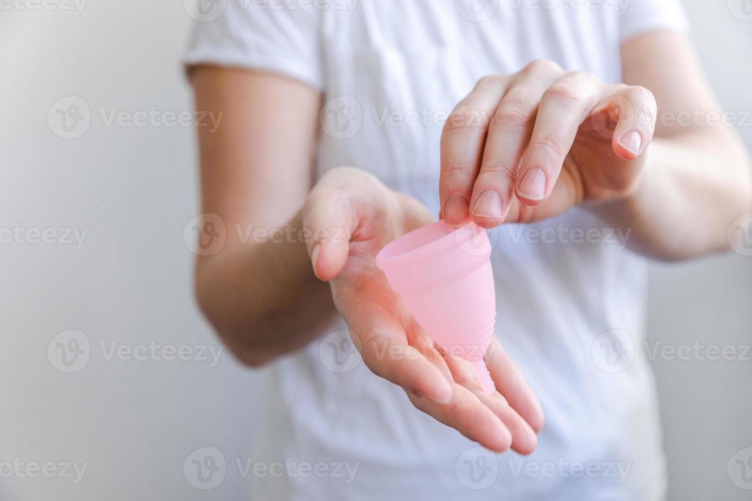 mão de uma mulher segurando o copo menstrual rosa isolado no fundo branco.  mulher moderna alternativa eco ginecológica higiene no período de  menstruação. recipiente para sangue na mão da menina. 5427428 Foto