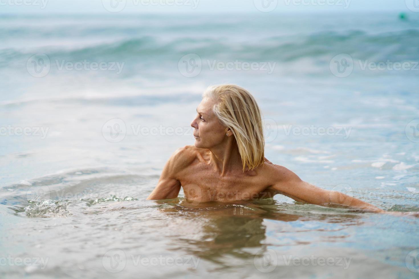 mujer madura en buena forma bañándose en el mar. foto
