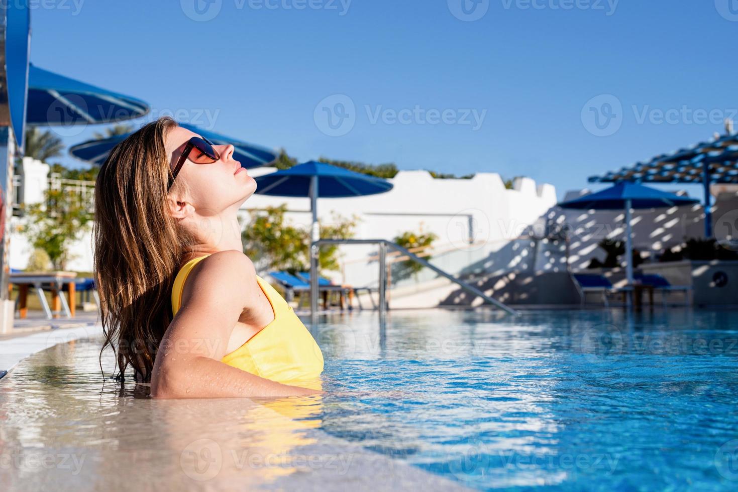 Young beautiful woman having fun swimming in the pool in summer photo