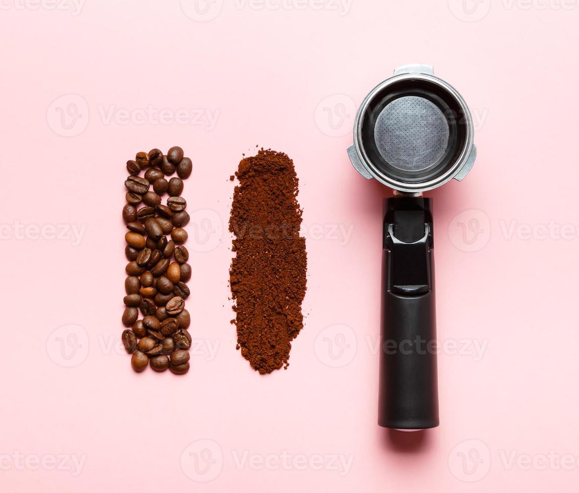 Espresso machine filter holder, ground coffee and coffee beans on pink background. photo