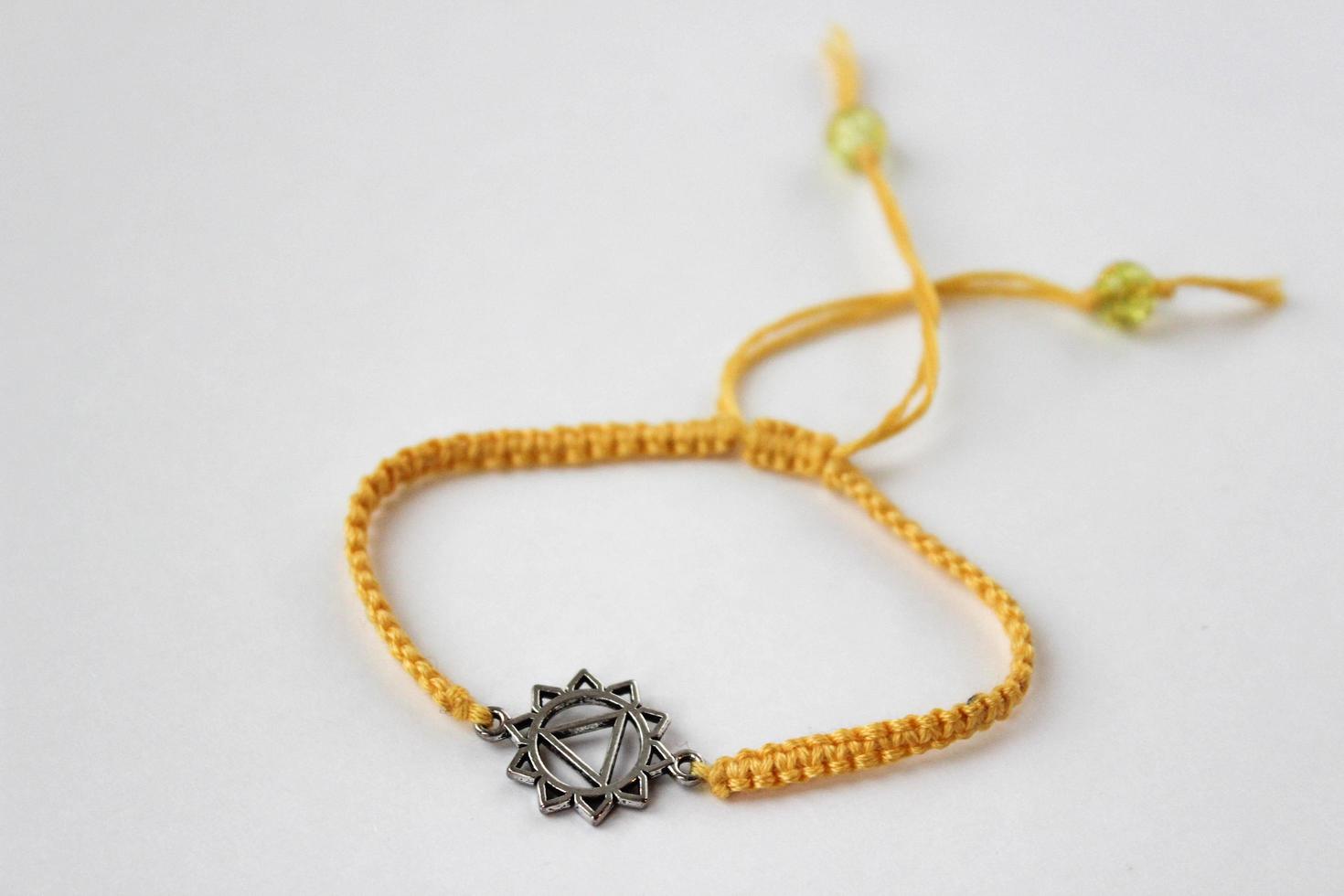 yellow braded bracelet with chakra manipura on white background photo