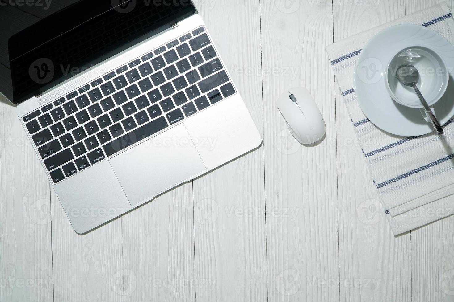 Top view of a laptop with a coffee mug on a white surface. photo