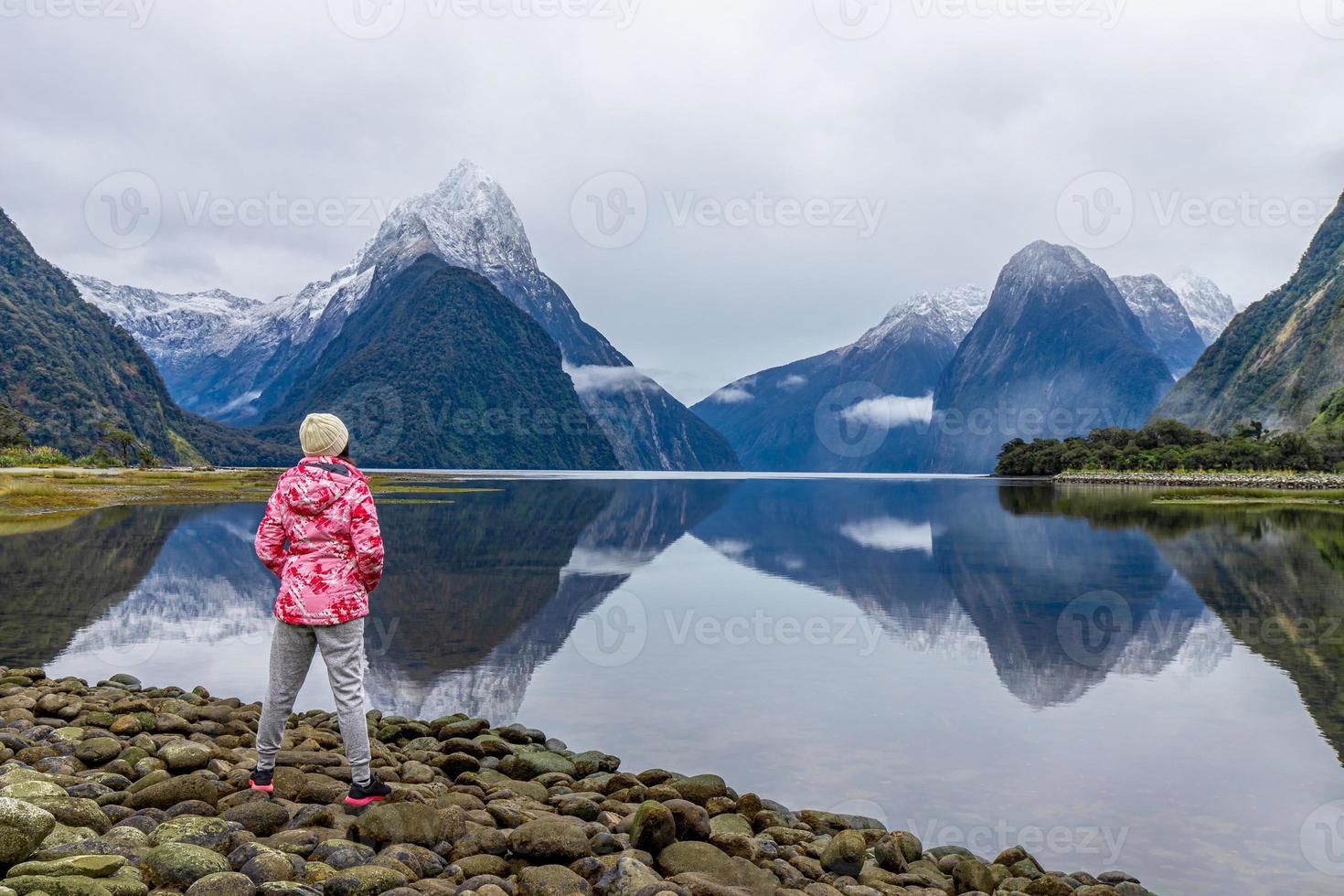 Young Asian traveler girl from back standing at Milford Sound, Fiordland National Park, South Island, New Zealand photo