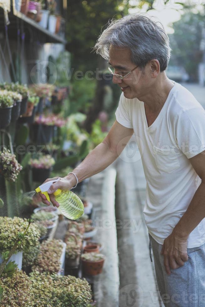 hombre asiático regando plantas caseras en el jardín de su casa foto