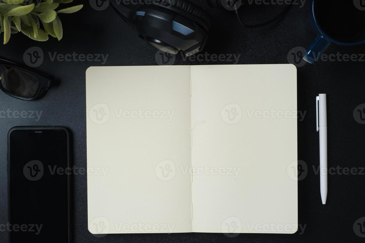 top view working desk with open notebook, headphone and mobile phone on black table background photo