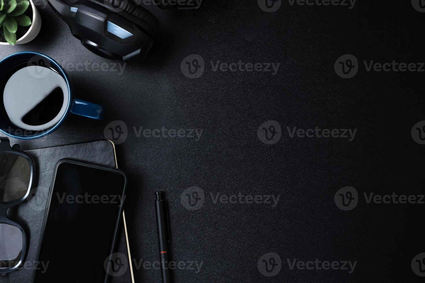 top view working desk with keyboard headphone and mobile phone on black table background photo