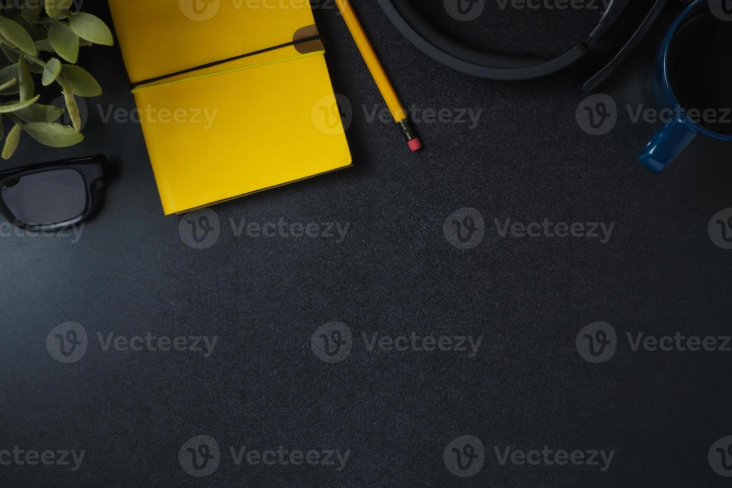 top view working desk notebook,headphone and coffee cup on black table background photo