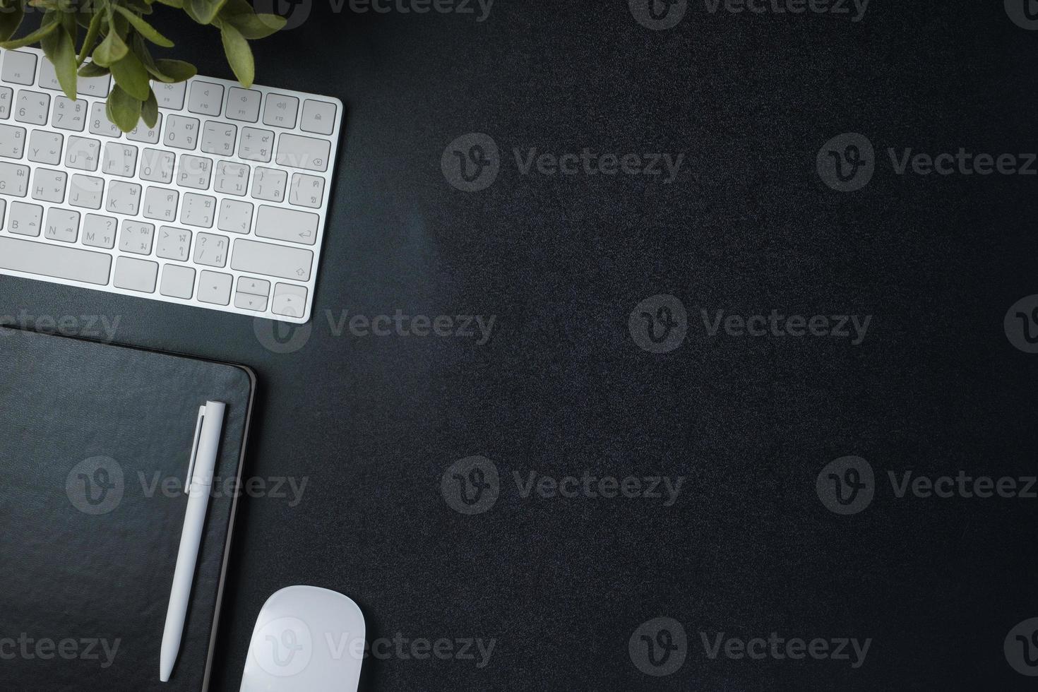 top view working desk with keyboard mouse and notebook on black table background photo