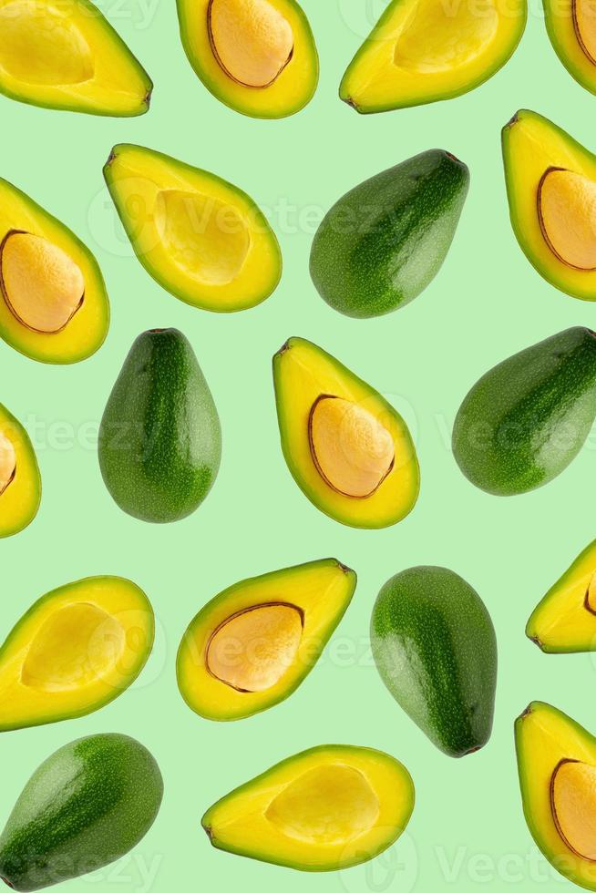 Slices and half of avocado isolated over a green background. photo