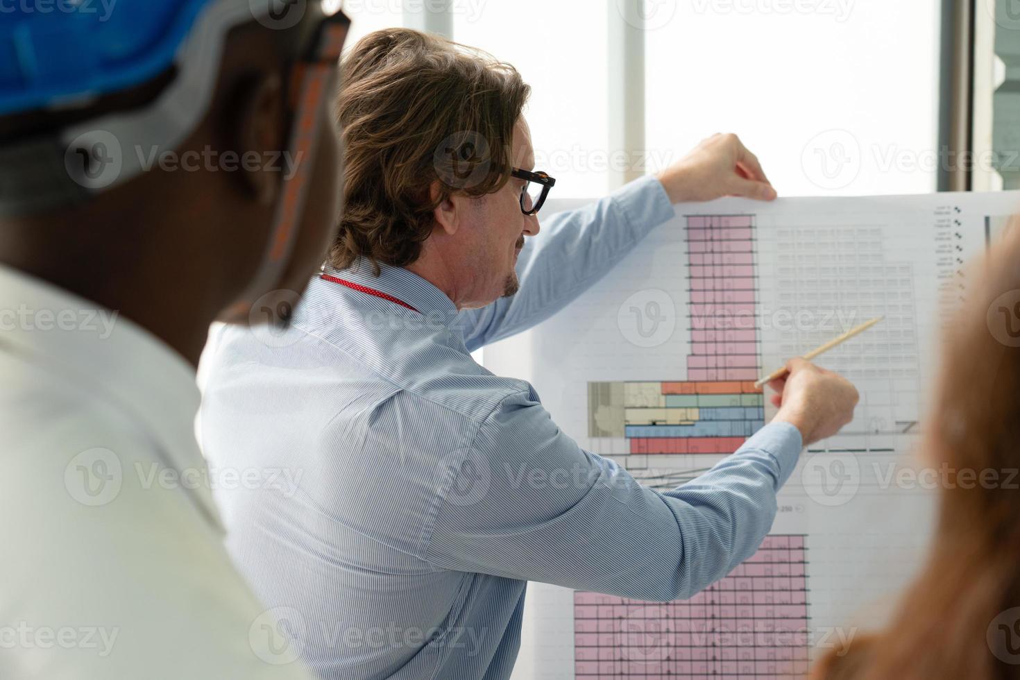 Middle Age Architect Explaining Floor Plan of Building to Client in Meeting photo