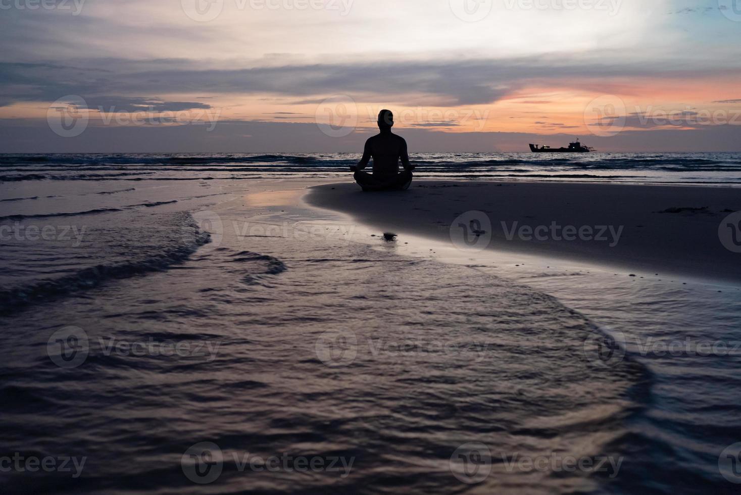 silueta de hombre meditar en la playa al atardecer foto
