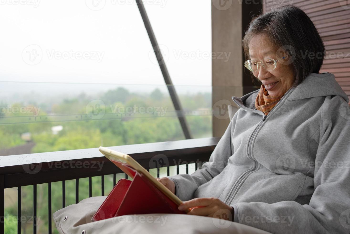 Senior mujer asiática con tableta digital en casa foto