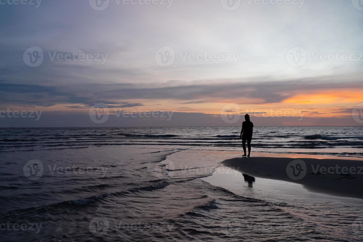 silueta de mujer parada en la playa al atardecer foto