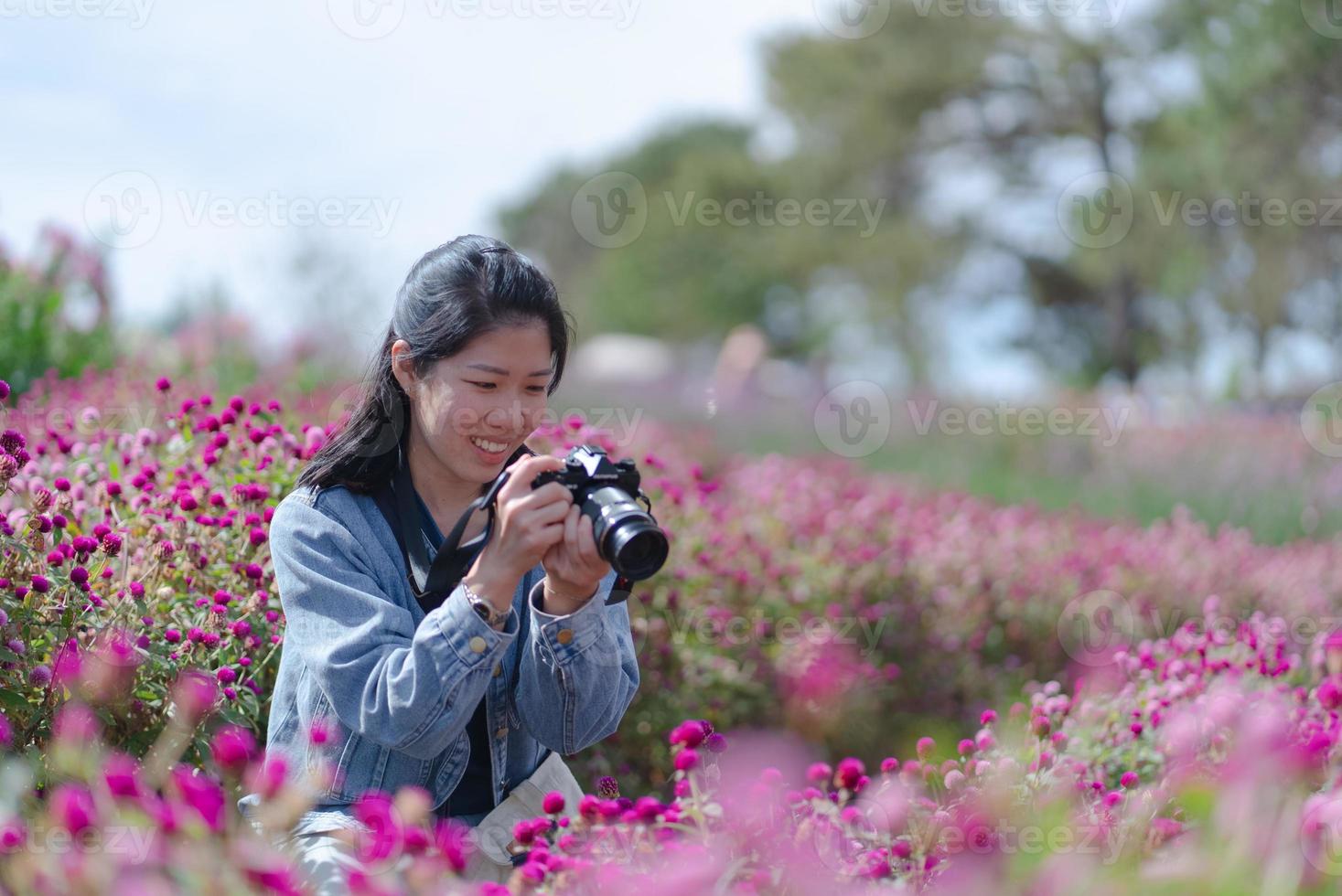 mujer asiática madura usando cámara para tomar fotos de flores al atardecer