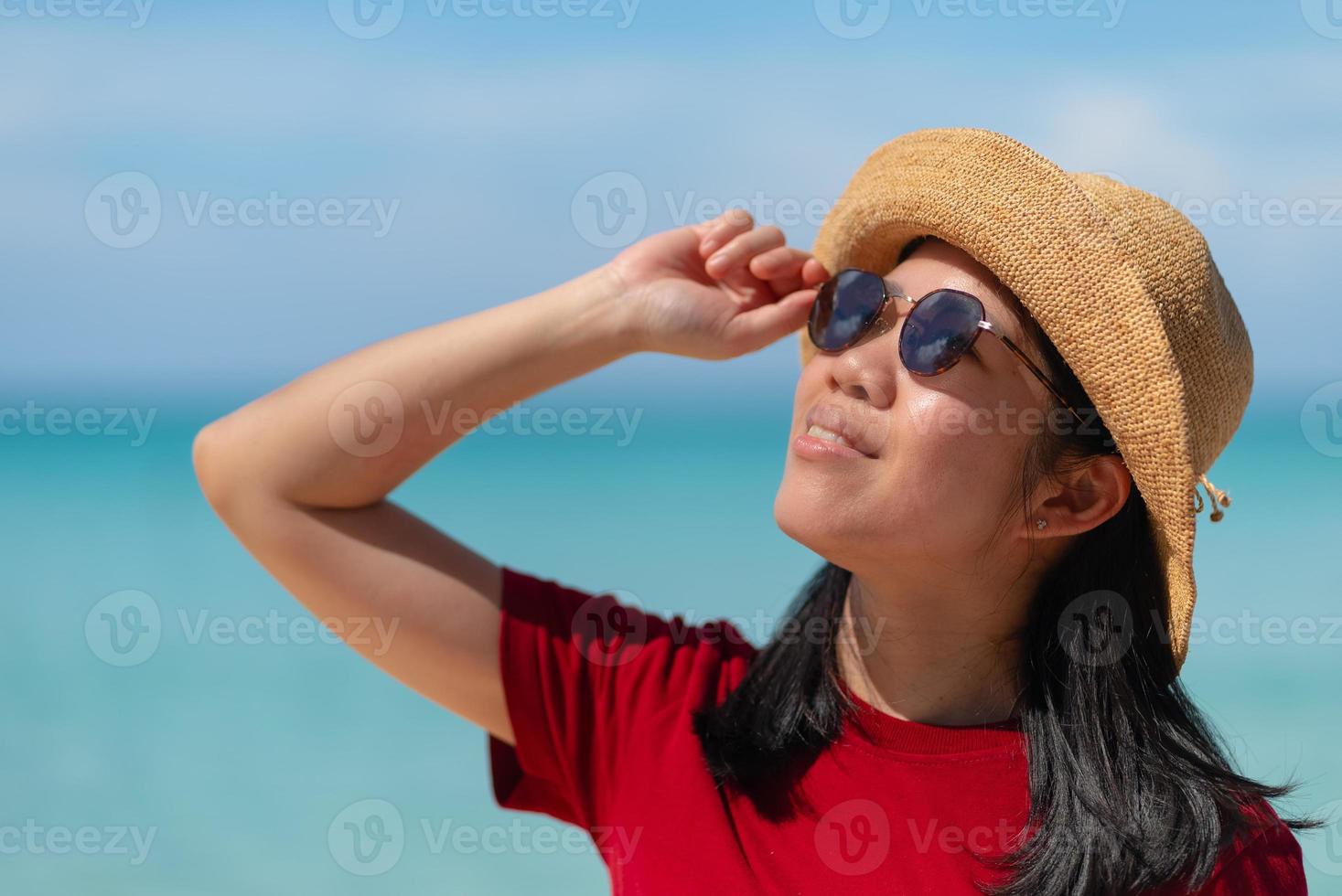 retrato de una mujer adulta madura asiática con gafas de sol con fondo oceánico foto
