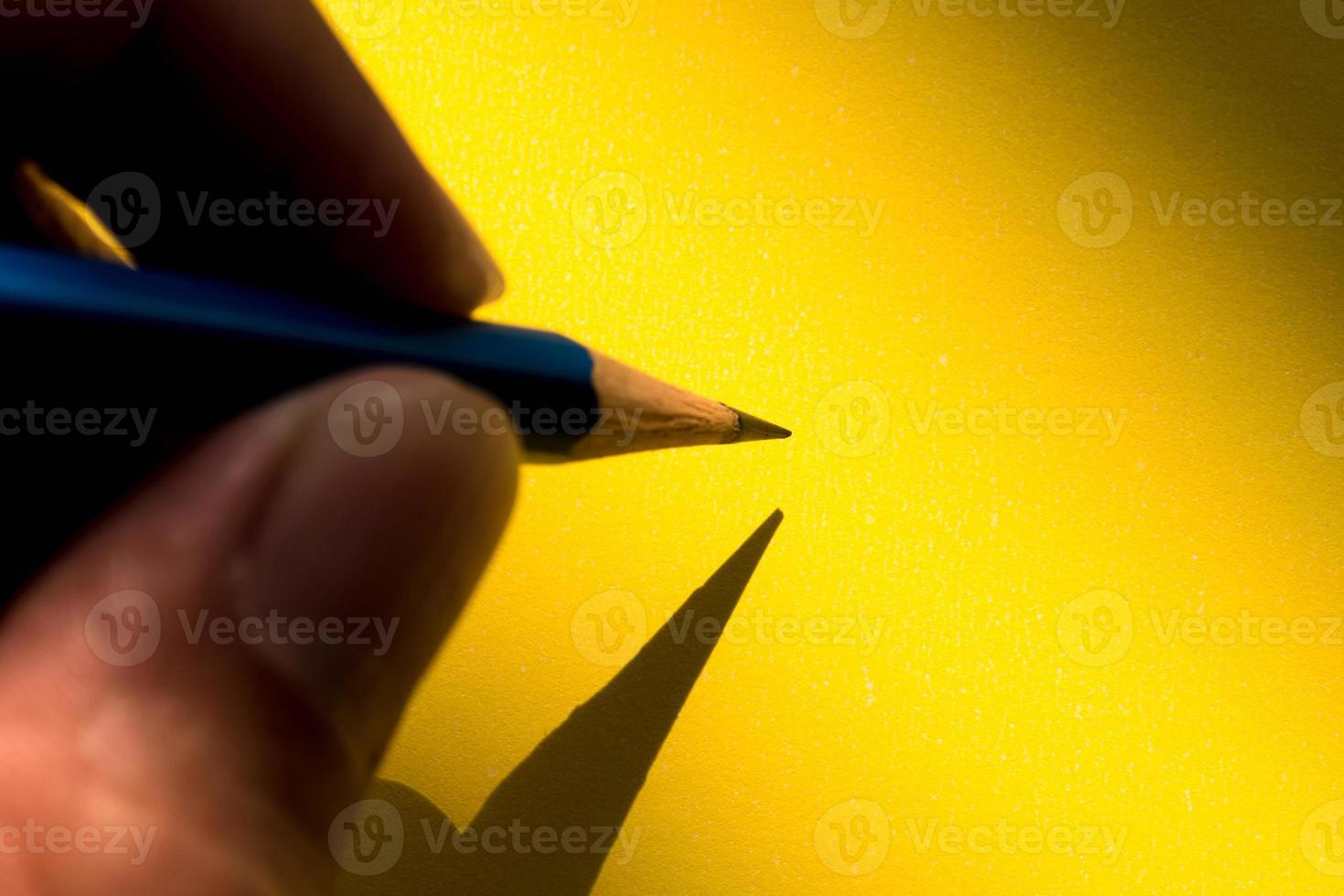 Human's hand holding pencil to write on the paper in shadow photo