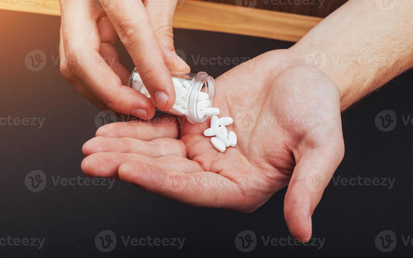 white tablets with a glass jar on a man's hand photo