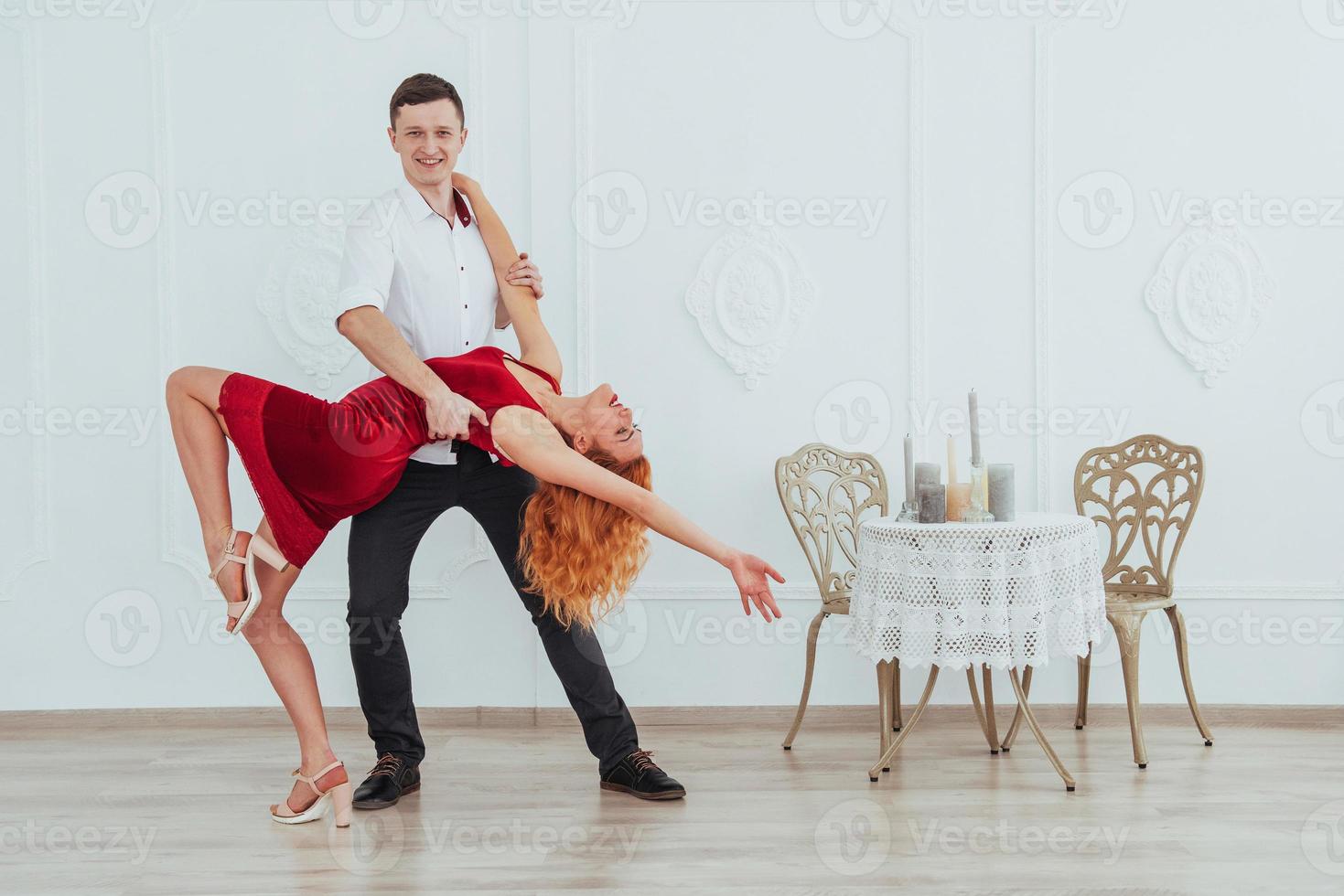 joven hermosa mujer con un vestido rojo y un hombre bailando, aislado en un fondo blanco. foto