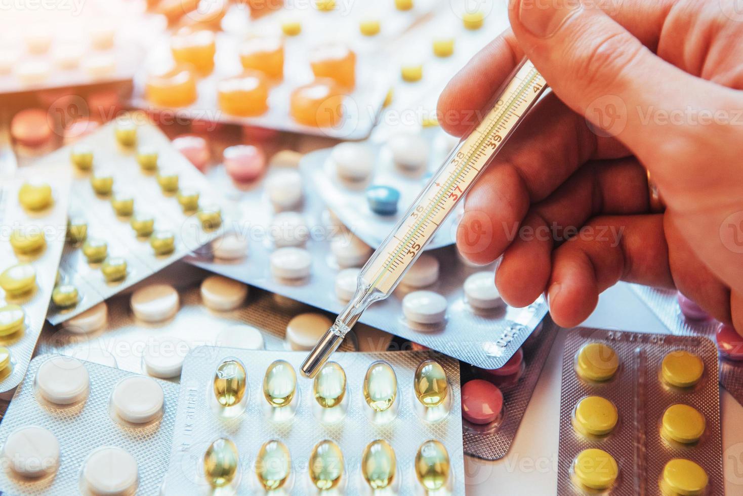 Thermometer and different colored types of pills. Medical health or drugs concept photo