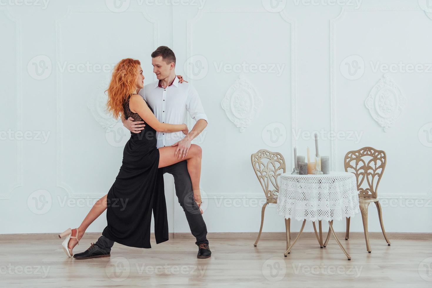 Young beautiful woman in a black dress and a man in white shirt dancing. photo