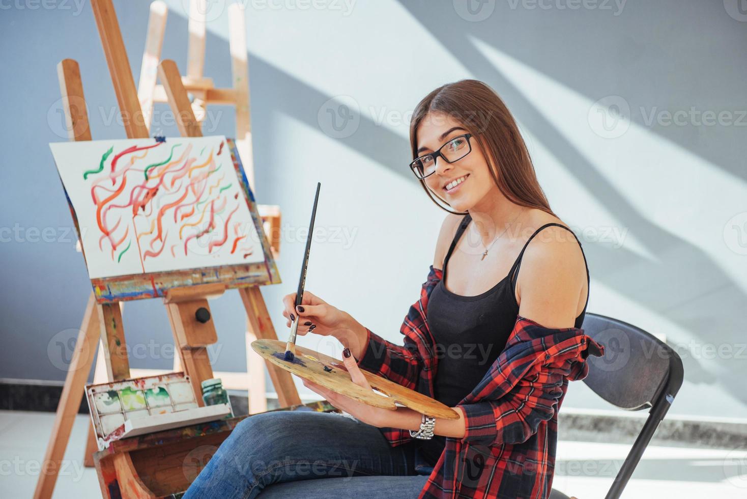 Creative pensive painter girl paints a colorful picture on canvas with oil colors in workshop photo