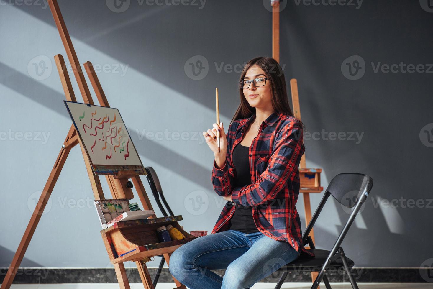 artista de pelo oscuro que sostiene un pincel en la mano y dibuja un cuadro sobre lienzo. piensa que se basa en foto