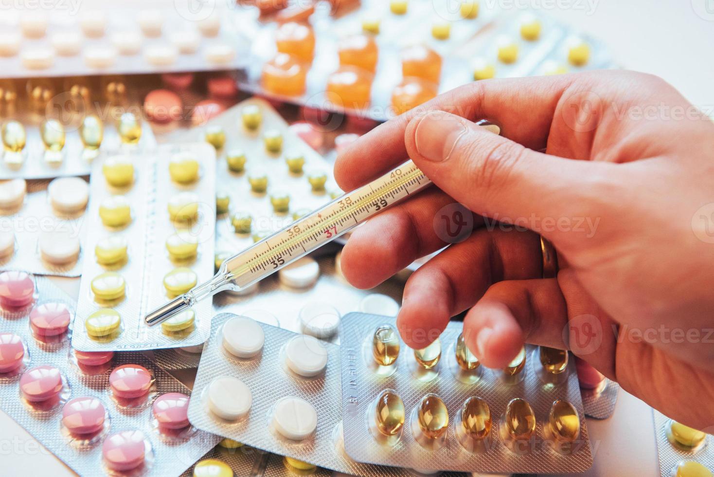 Thermometer and different colored types of pills. Medical health or drugs concept photo