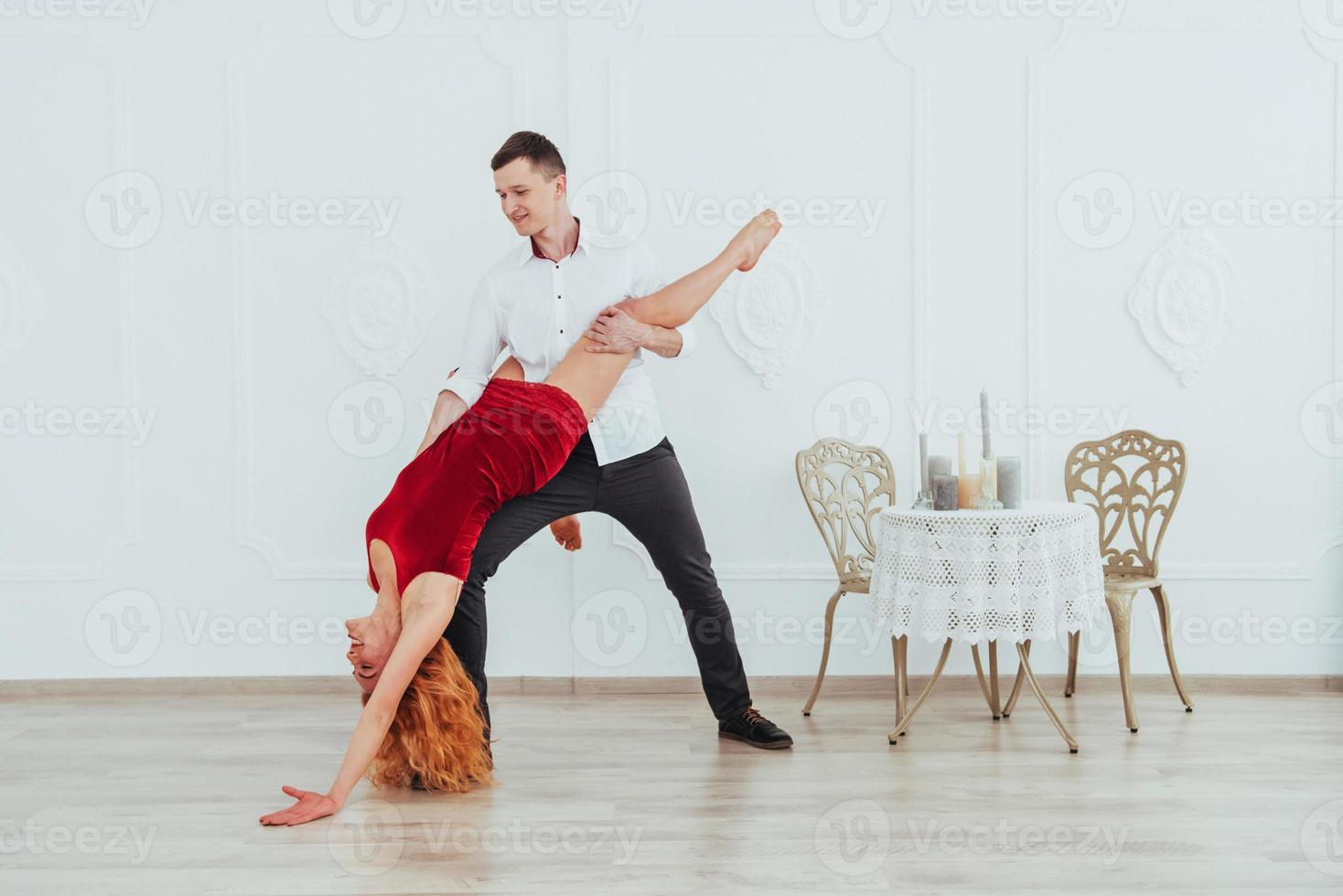 Young beautiful woman in a red dress and a man dancing, isolated on a white background. photo
