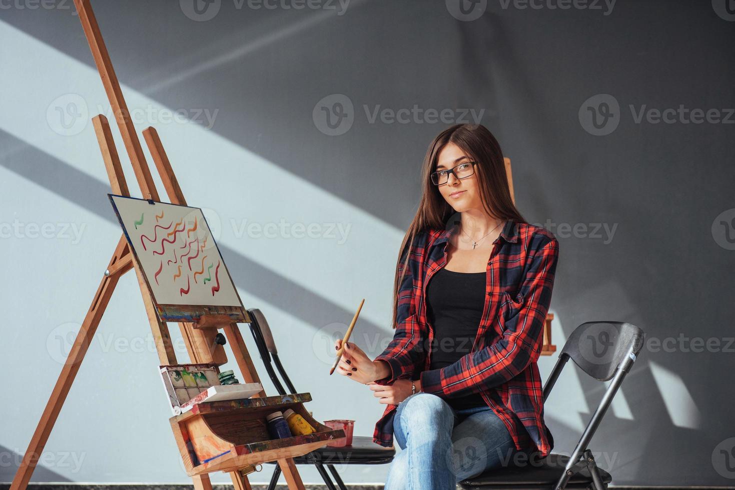 Dark-haired artist holding a brush in his hand and draws a picture on canvas. Thinks that draw on photo