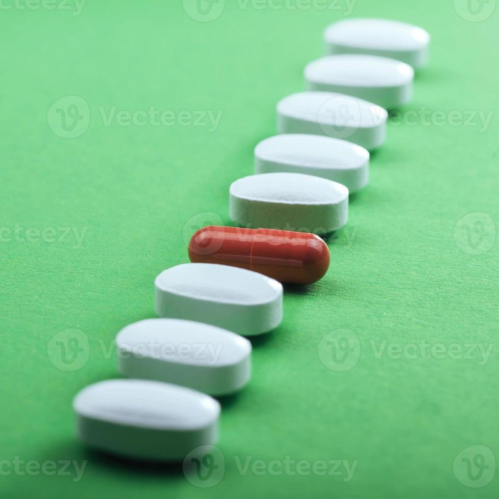 Medical white pills and brown capsules for the treatment and health care on a green background photo