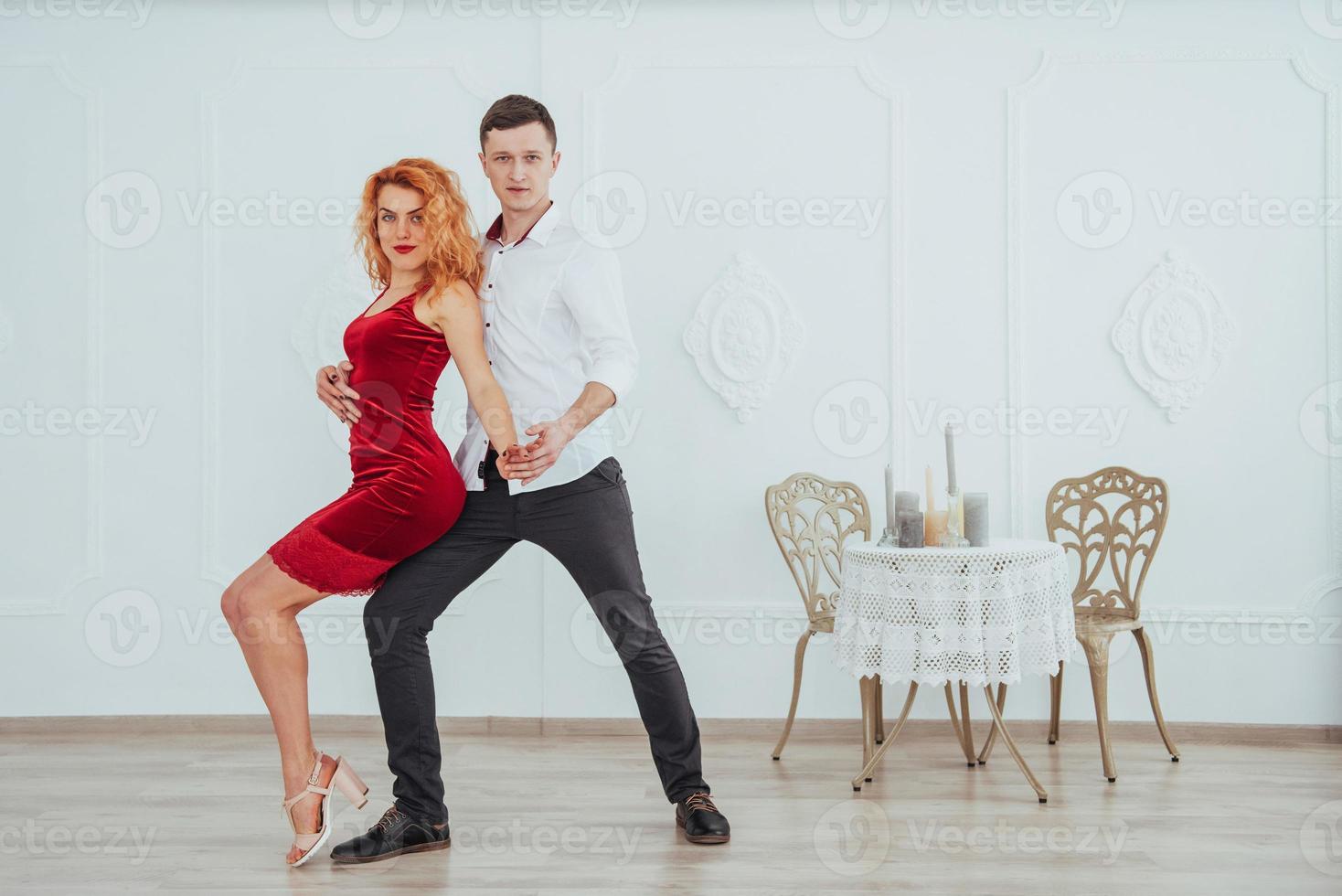 Young beautiful woman in a red dress and a man dancing, isolated on a white background. photo