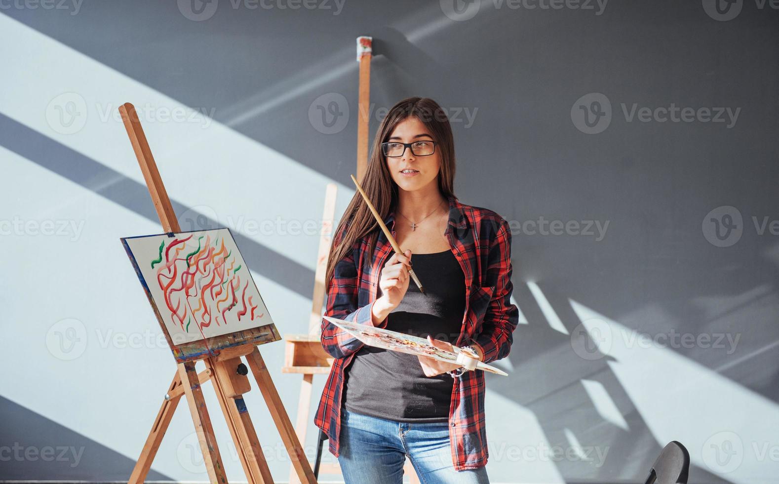 Dark-haired artist holding a brush in his hand and draws a picture on canvas. Thinks that draw on photo