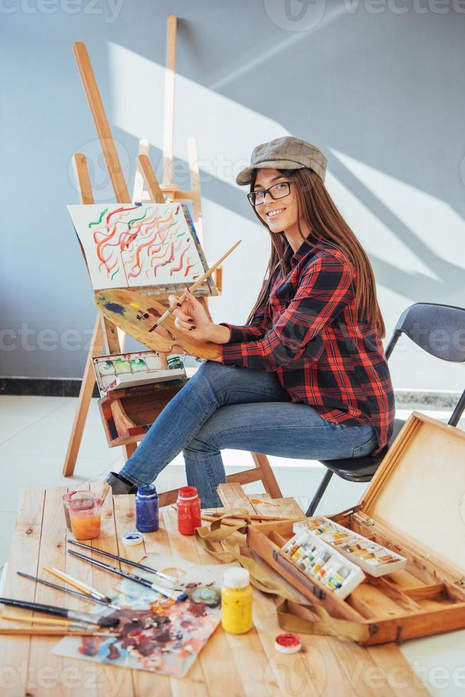 Creative pensive painter girl paints a colorful picture on canvas with oil colors in workshop photo