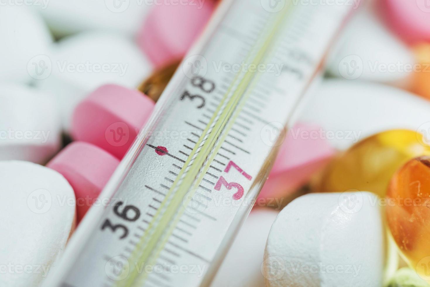 Thermometer and different colored types of pills. Medical health or drugs concept photo